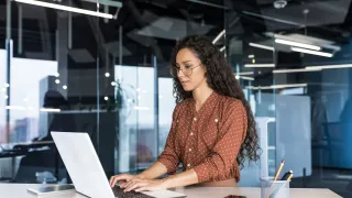 A woman is sitting on a desk with a notebook